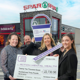 Image shows two AMH employees and two Henderson Group employees standing in front of of a SPAR store. They are holding a large cheque.