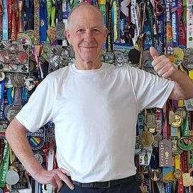 Oggie giving the thumbs up in front of his wall of medals