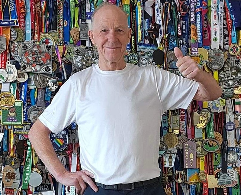 Oggie giving the thumbs up in front of his wall of medals