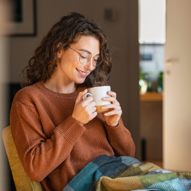 Girl in early twenties sits at home with a cup of tea.