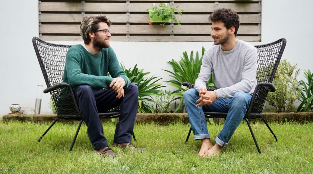 Two men sitting in a garden talking.