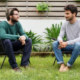 Two men sitting in a garden talking.