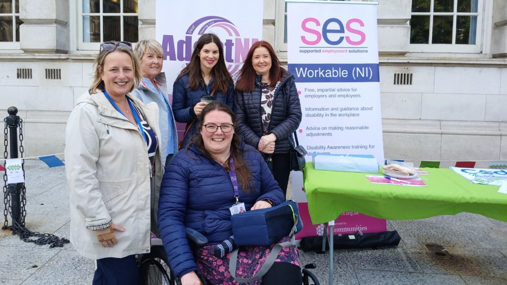 A group of participants and staff from Workable (NI) in front of the SES banner at the Big Lunch event.