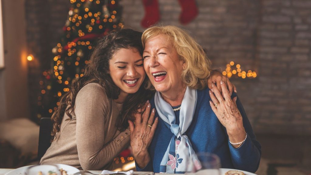 A young woman hugging her grandmother while they enjoy Christmas dinner.