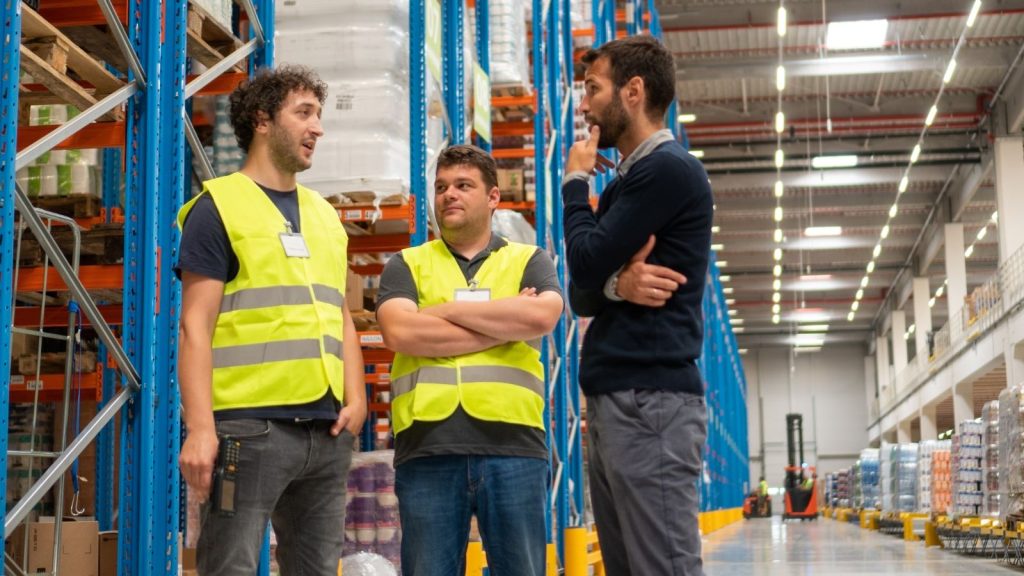 Two warehouse workers talking to a manager. 