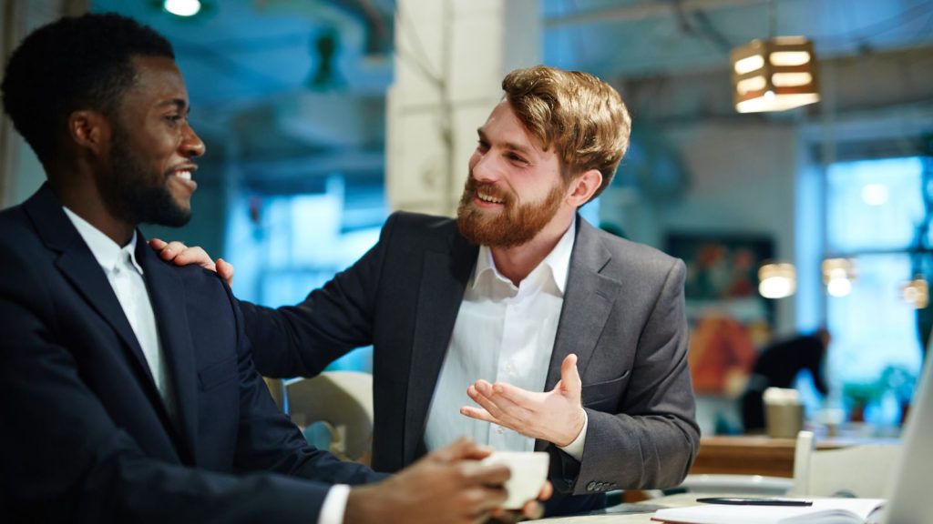 Two colleagues in an office, talking and smiling.