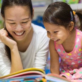A mother and young daughter reading a children's book in a library.