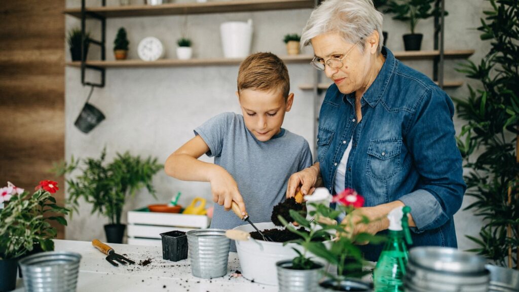 A boy helping his grandmother to plant flowers.