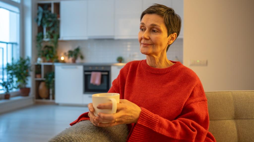 A middle-aged woman sitting on a sofa, peacefully drinking tea.